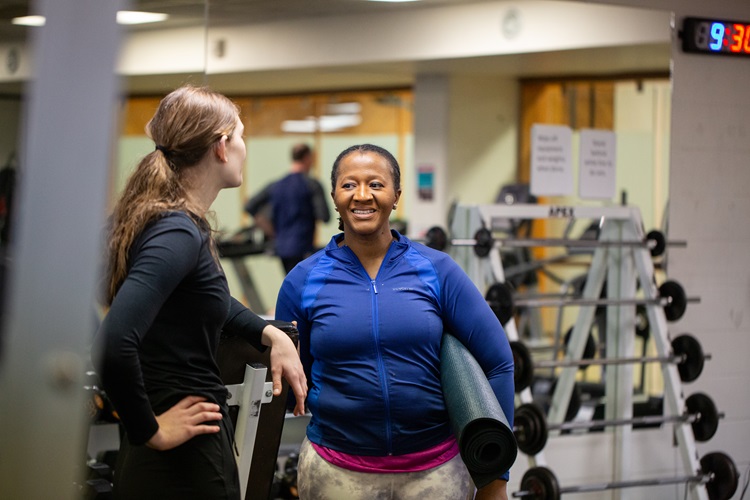 Two people standing in weight room